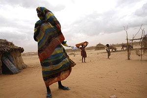 In the Rwanda displaced persons camp in Tawilla, a woman and her children stand in front of their hut as a sandstorm approaches.