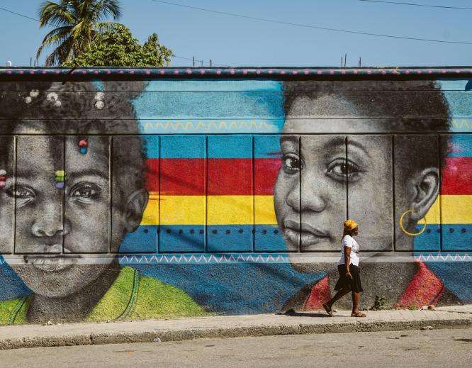 A woman walks past a mural in Bois-Verna, a residential area of Port-au-Prince.