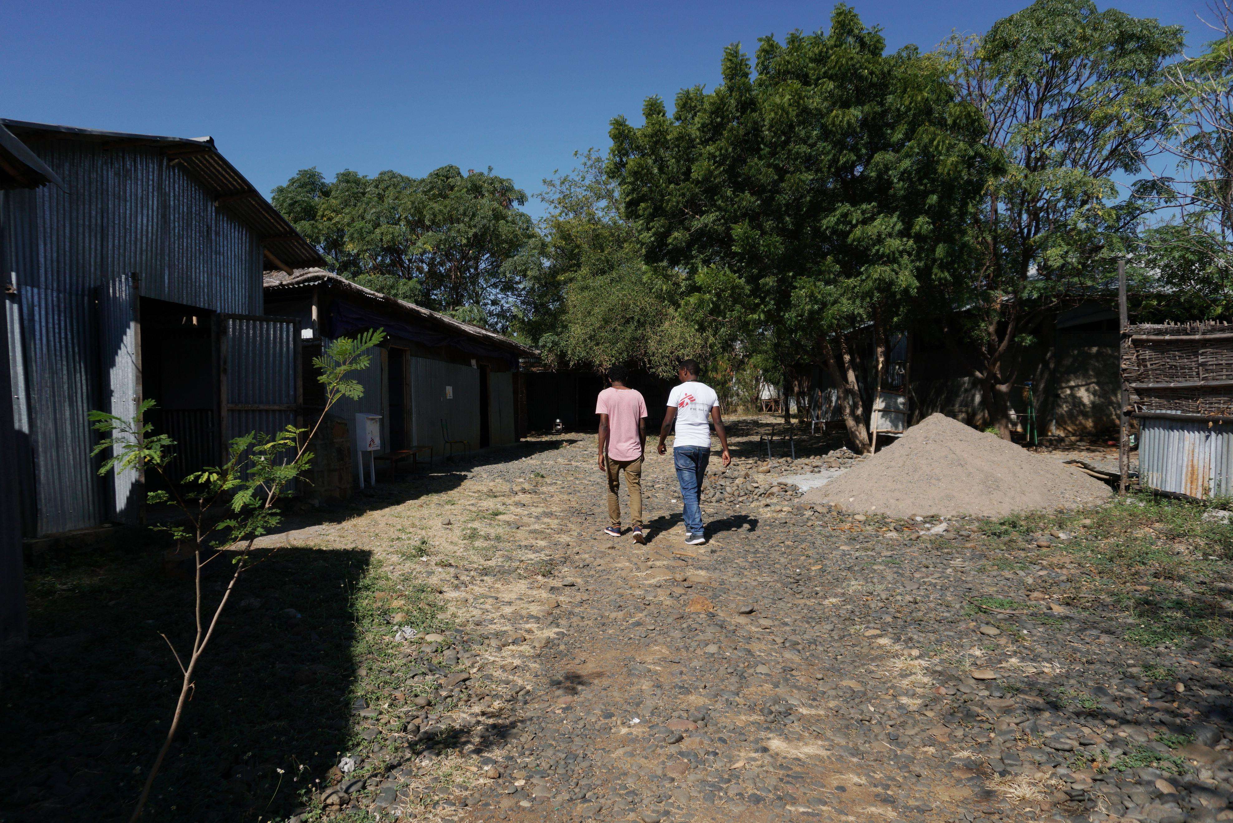 Two people walking down a dirt road