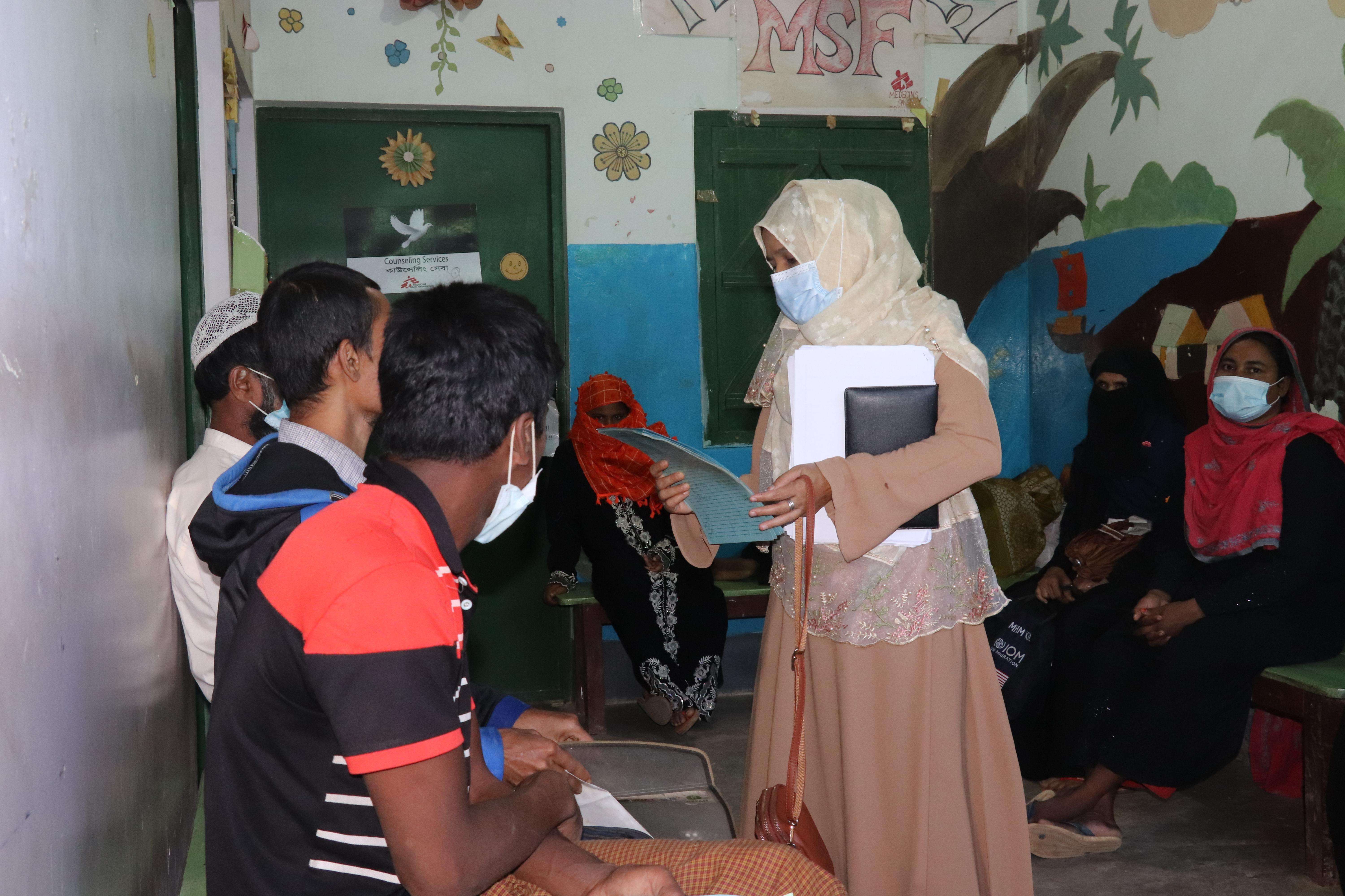 A medic speaks to a group of patients who wait 