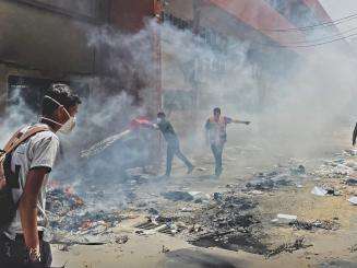 Palestinians walk through smoke in the streets of Gaza.