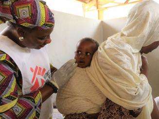 MSF field worker interacting with a mother and her son seeking treatment at a health center administering the Meningitis vaccination campaign in Niamey region.