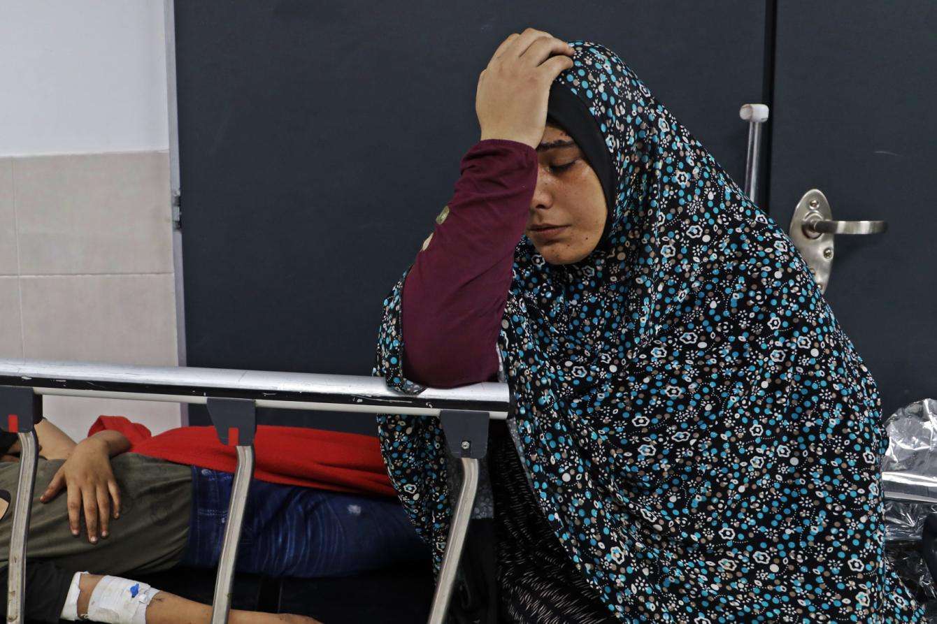 A Palestinian woman holds her head in her hand at Al-Shifa Hospital in Gaza.