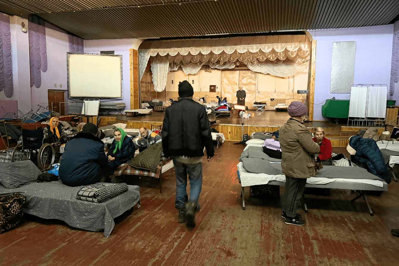 People sit on cots in a shelter in Ukraine. 