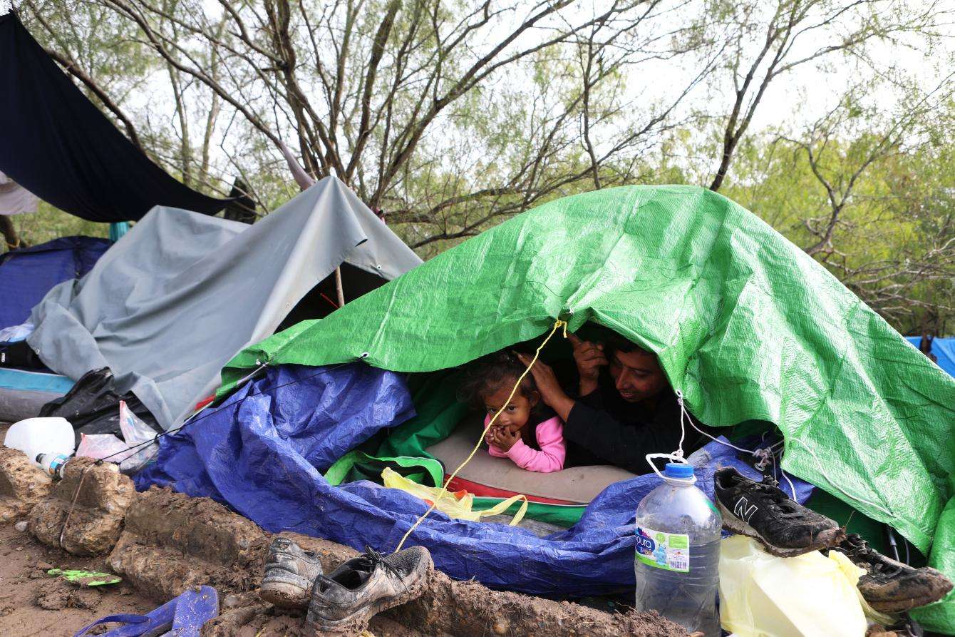 A family peeks out of their tent on a very cold day at an encampment near the international bridge connecting Matamoros, Mexico, with Brownsville, Texas.