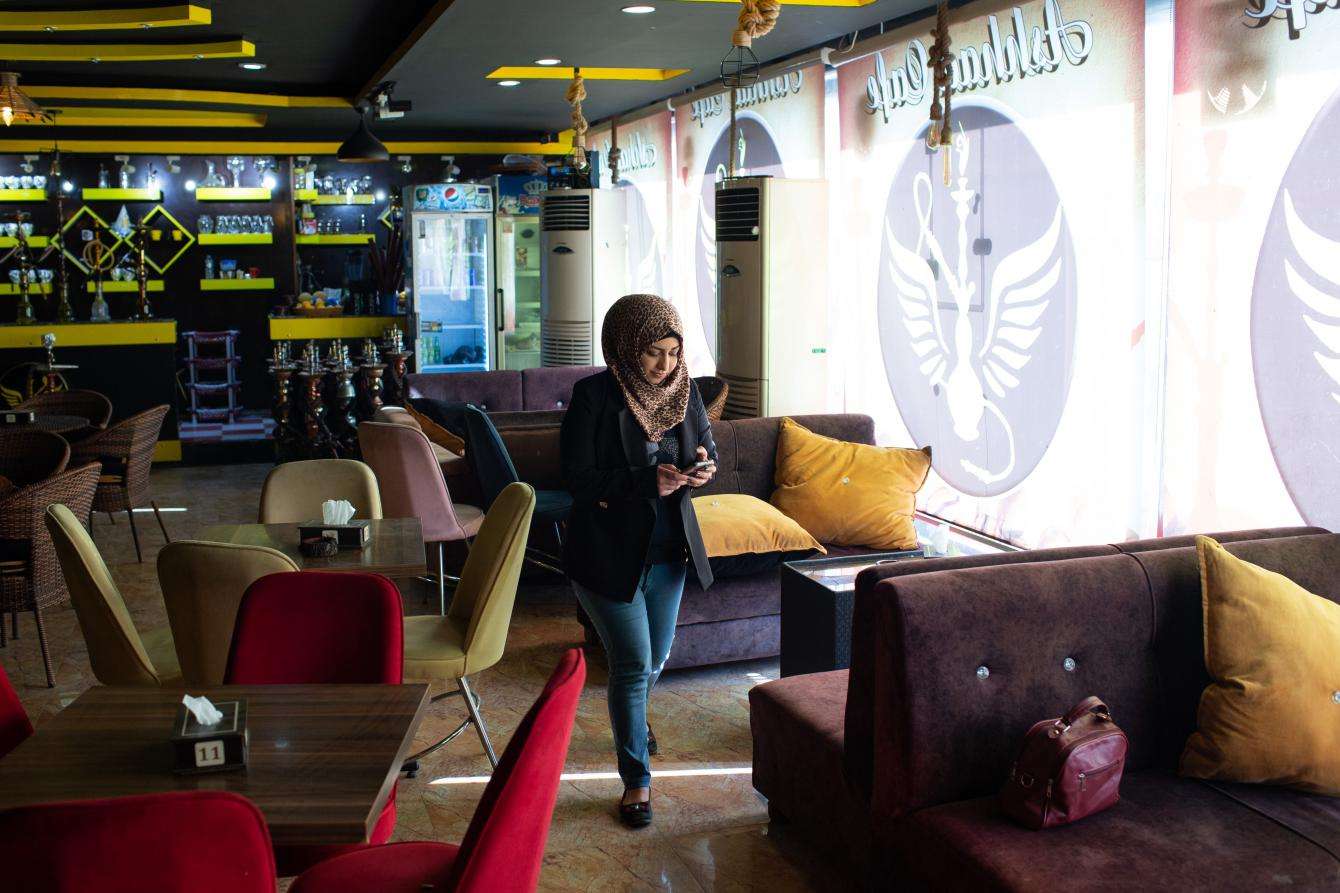 A woman walking through a coffee shop, checking her phone