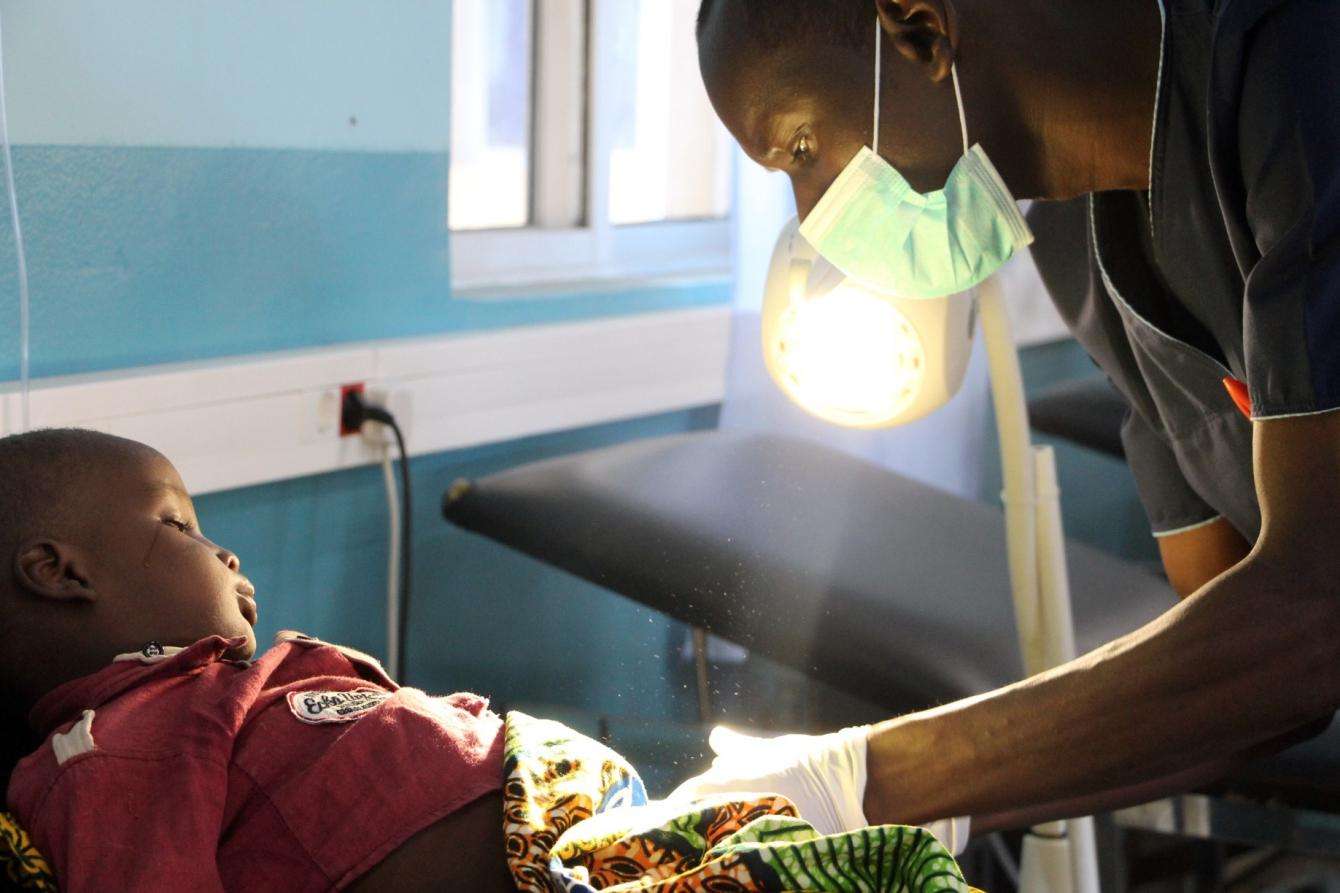 A doctor treats a child under warm light.