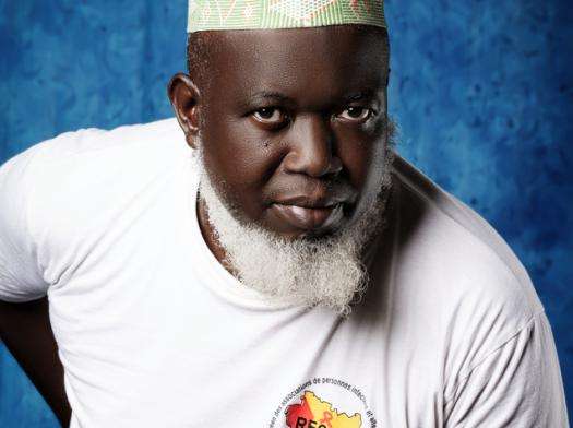 A man with hand on his back in white T-shirt.