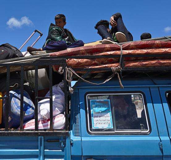 Displaced Palestinians on a truck packed with belongings in Gaza.